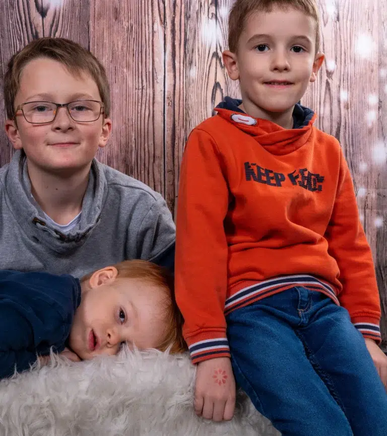 drei kinder sitzen auf einer bank in einem fotostudio