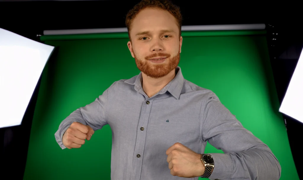 Mann mit erhobenen Fäusten, von Studiolampen gerahmt, grüner Hintergrund