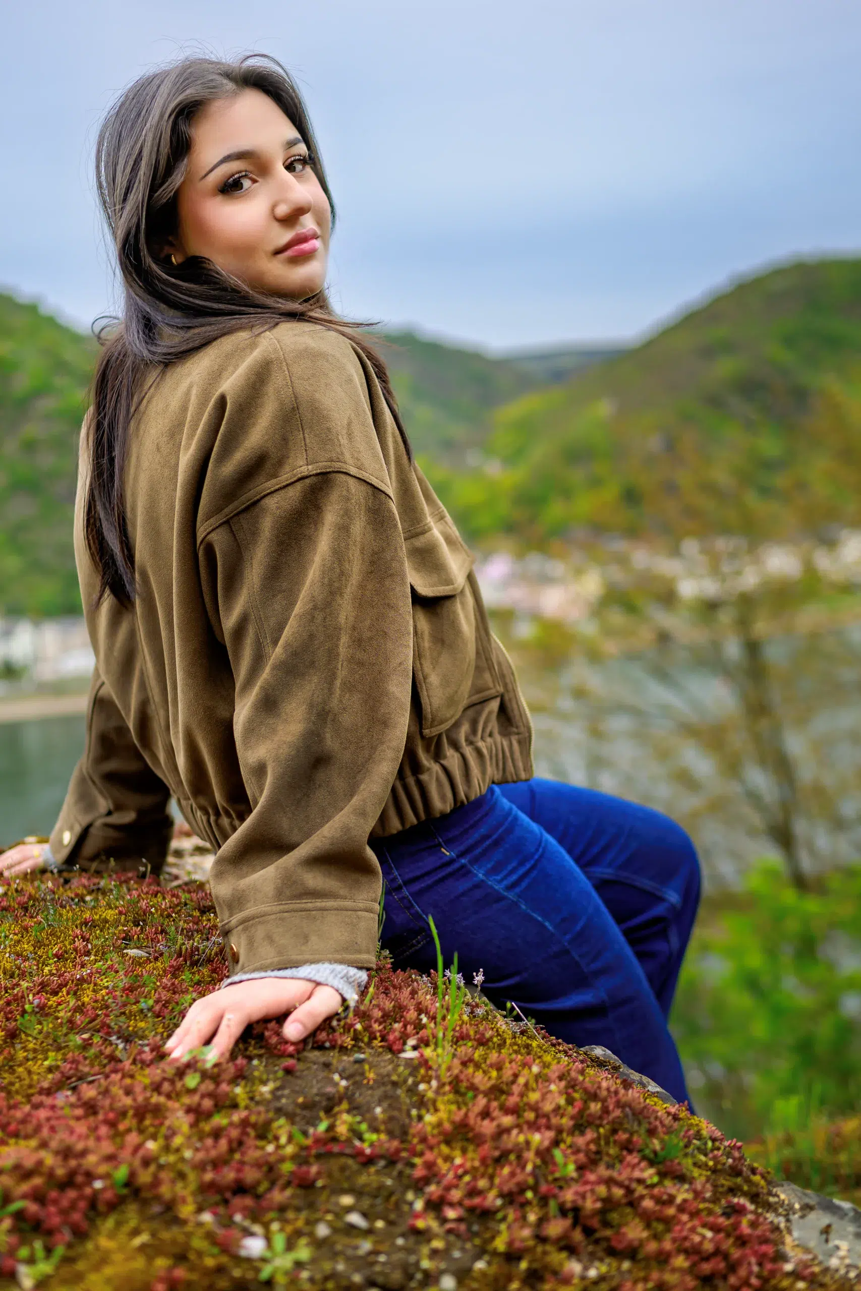 Junge Frau sitzt auf einem Felsen mit Aussicht bei einem Portrait Shooting