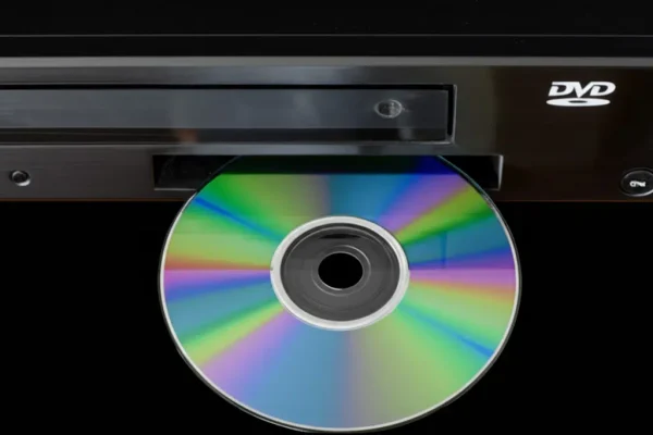 Eine DVD wird gerade in das geöffnete Fach eines schwarzen DVD-Players eingeschoben. Das "DVD"-Logo ist auf dem Player erkennbar. Dieses Szenario symbolisiert die Wiedergabe von Filmen und Fotos von DVDs, die durch den Digitalsierungsservice Foto-Video-Peters in Boppard auf USB-Sticks übertragen werden können.