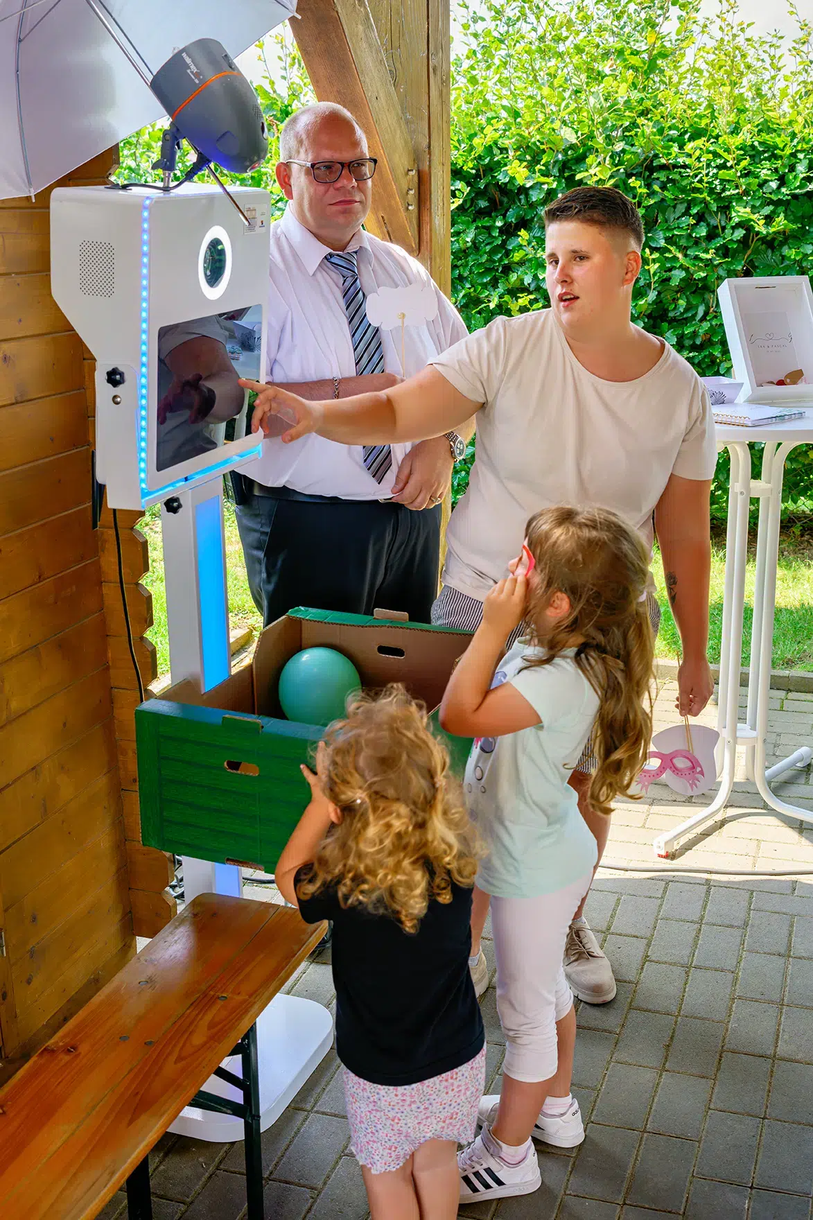 Gäste einer Feier im Freien, darunter zwei kleine Mädchen und Erwachsene,