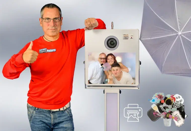 Fotobox-System mit Bildschirm und Blitz, präsentiert von Ralf Peters in rotem Shirt.