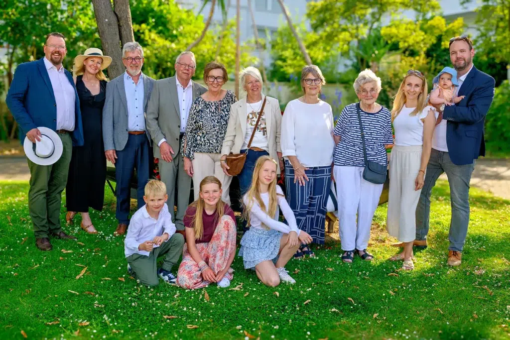 Großes Familienfotoshooting mit vier Generationen im Freien auf einer grünen Wiese,