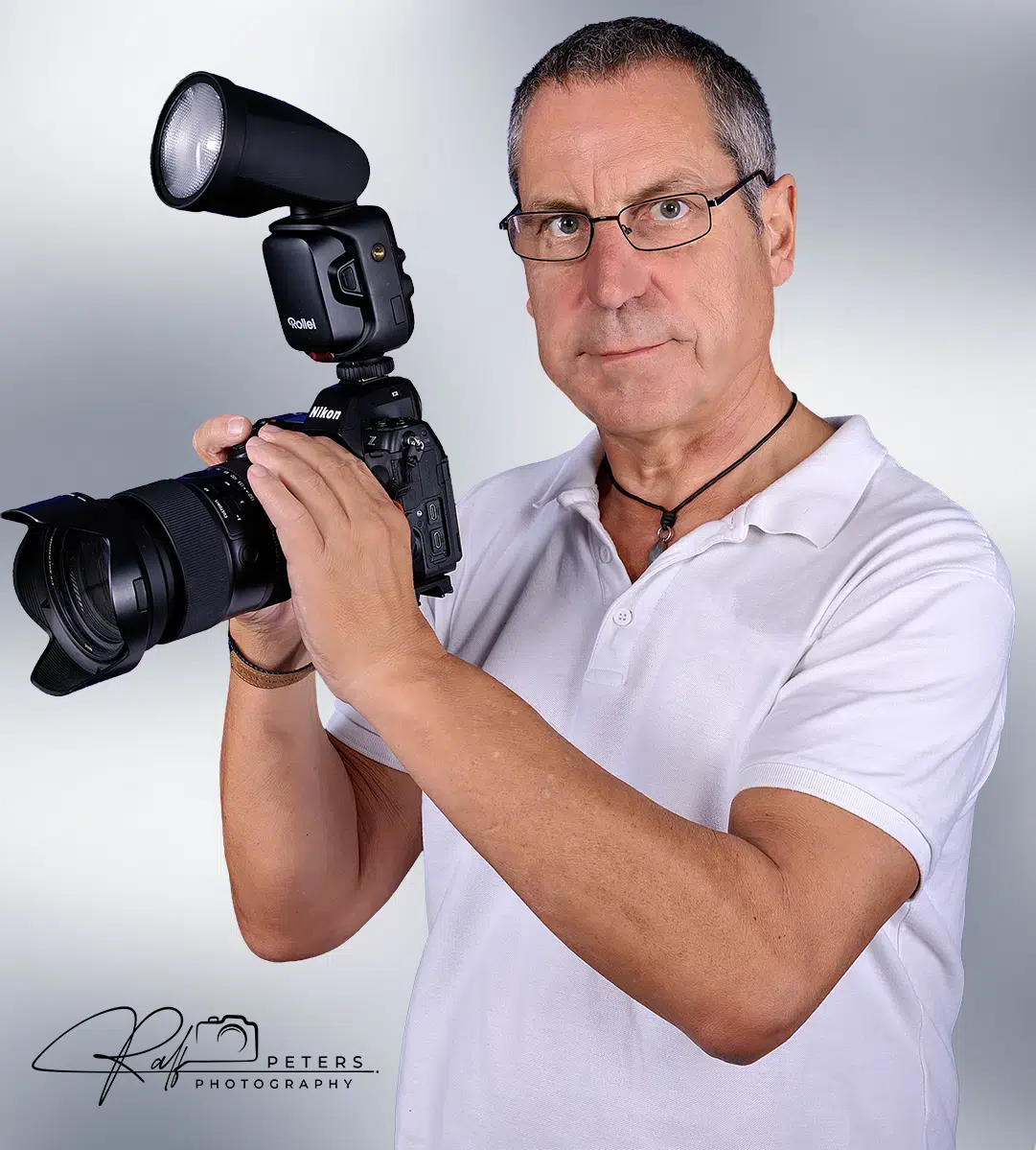 Ralf Peters, Fotograf, mit DSLR-Kamera – Studio-Porträt.